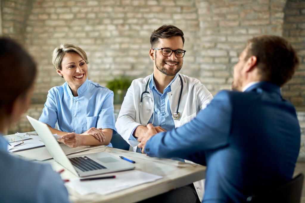 Happy doctor shaking hands with a businessman on a meeting in th